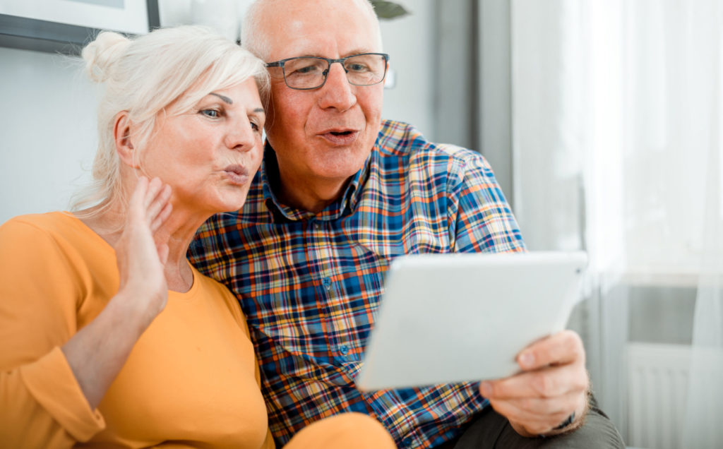 Happy senior couple video chatting using tablet at home