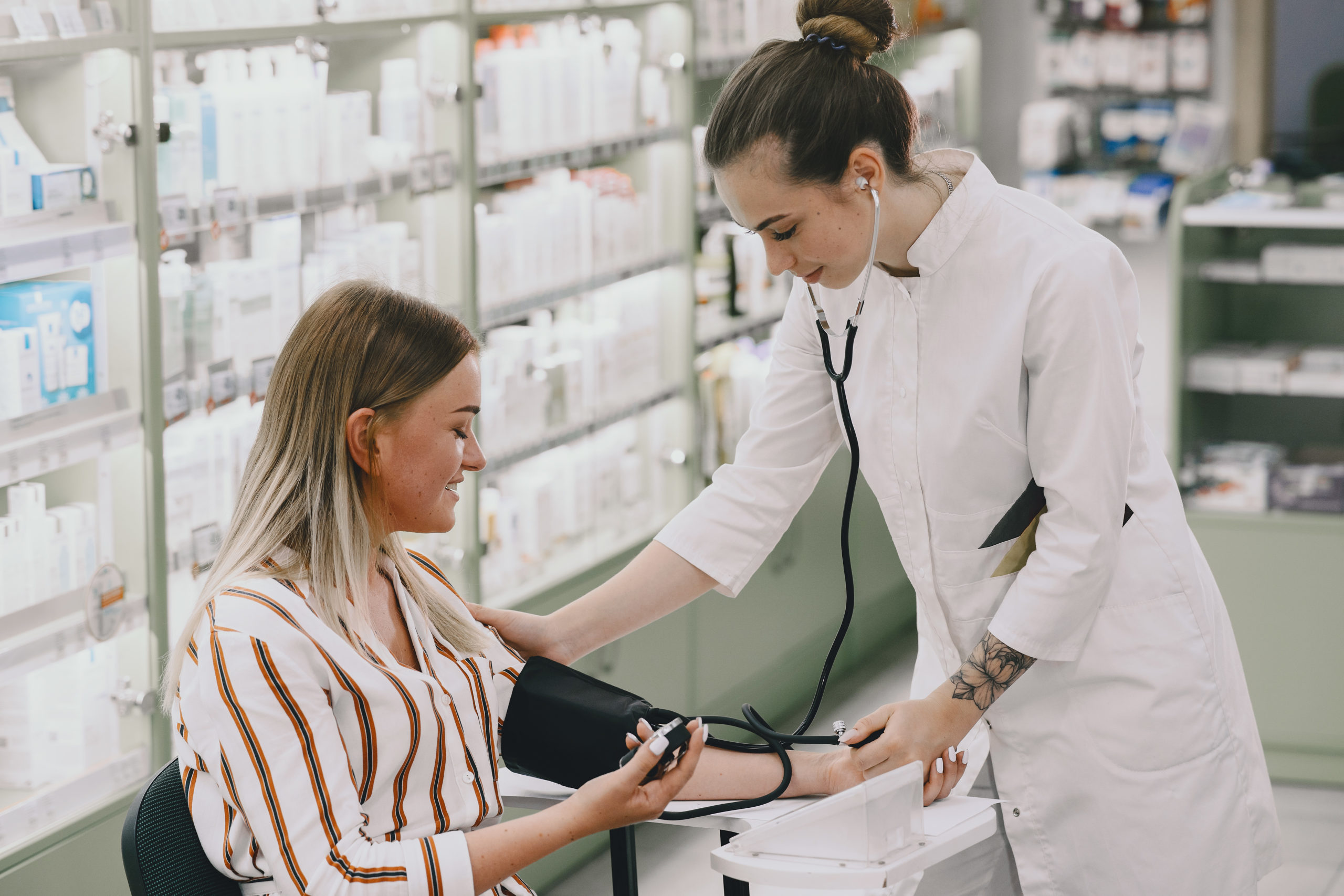 Trainee taking blood pressure of his customer in the pharmacy